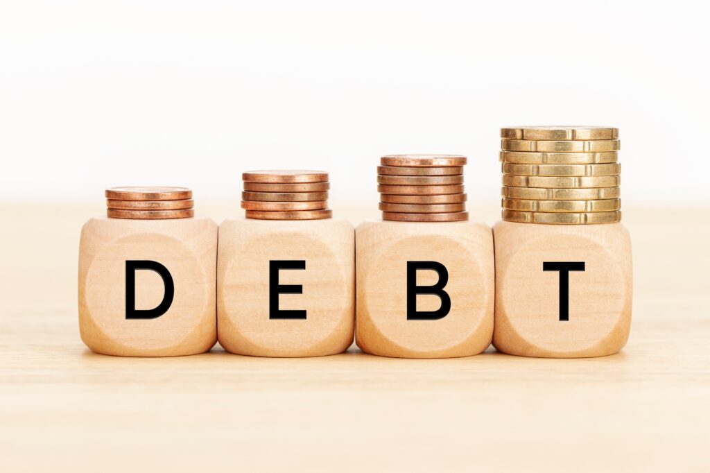 Debt concept. Wooden blocks with text and coins on wooden table