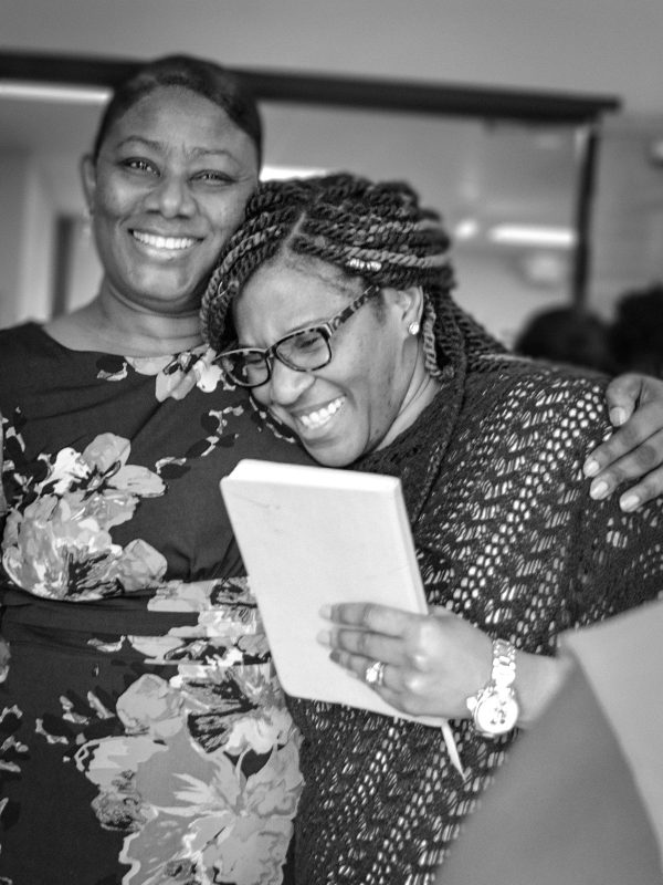 Two women hug and smile after church service.